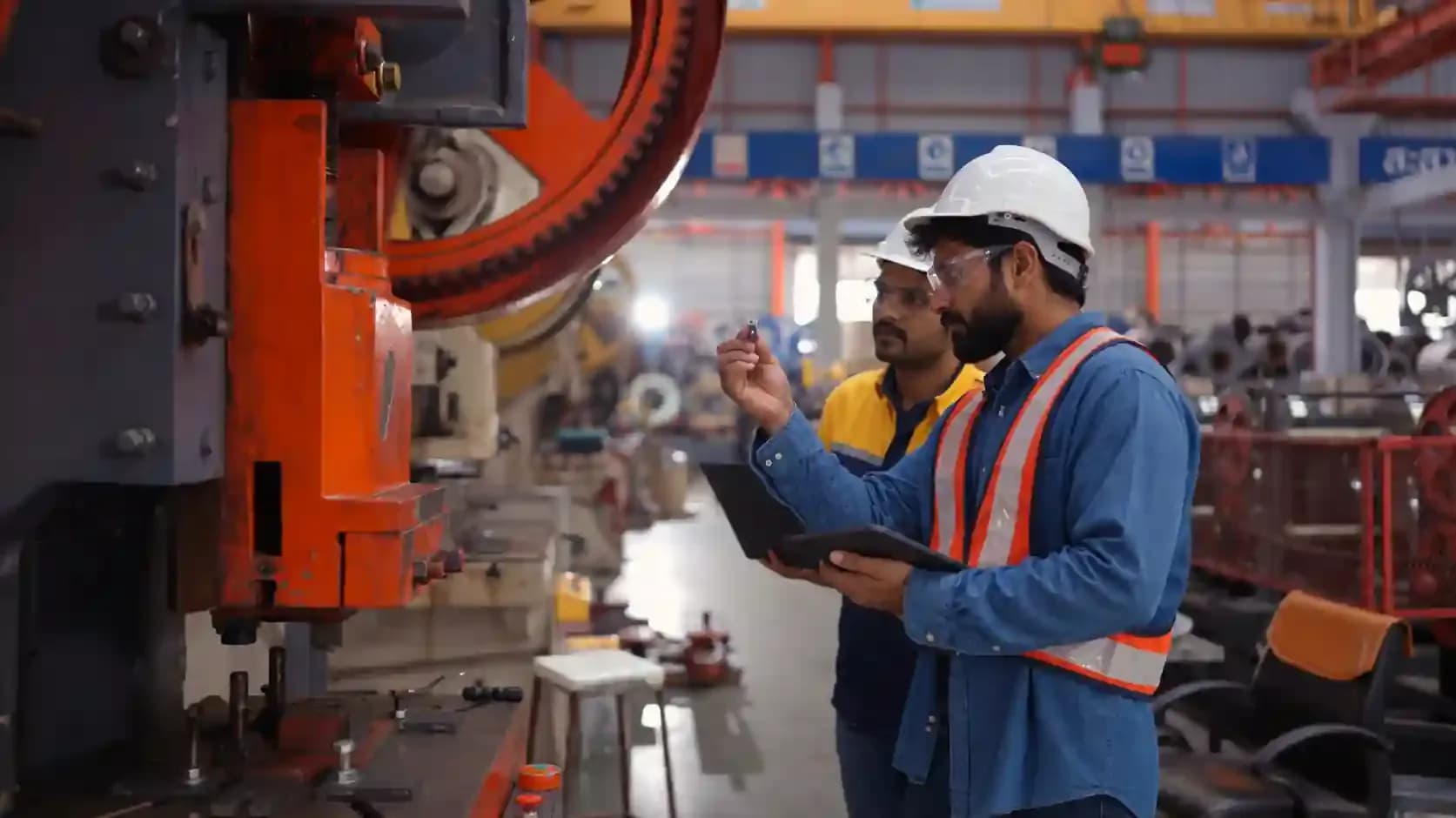 An engineer and technician discussing machinery on a factory floor