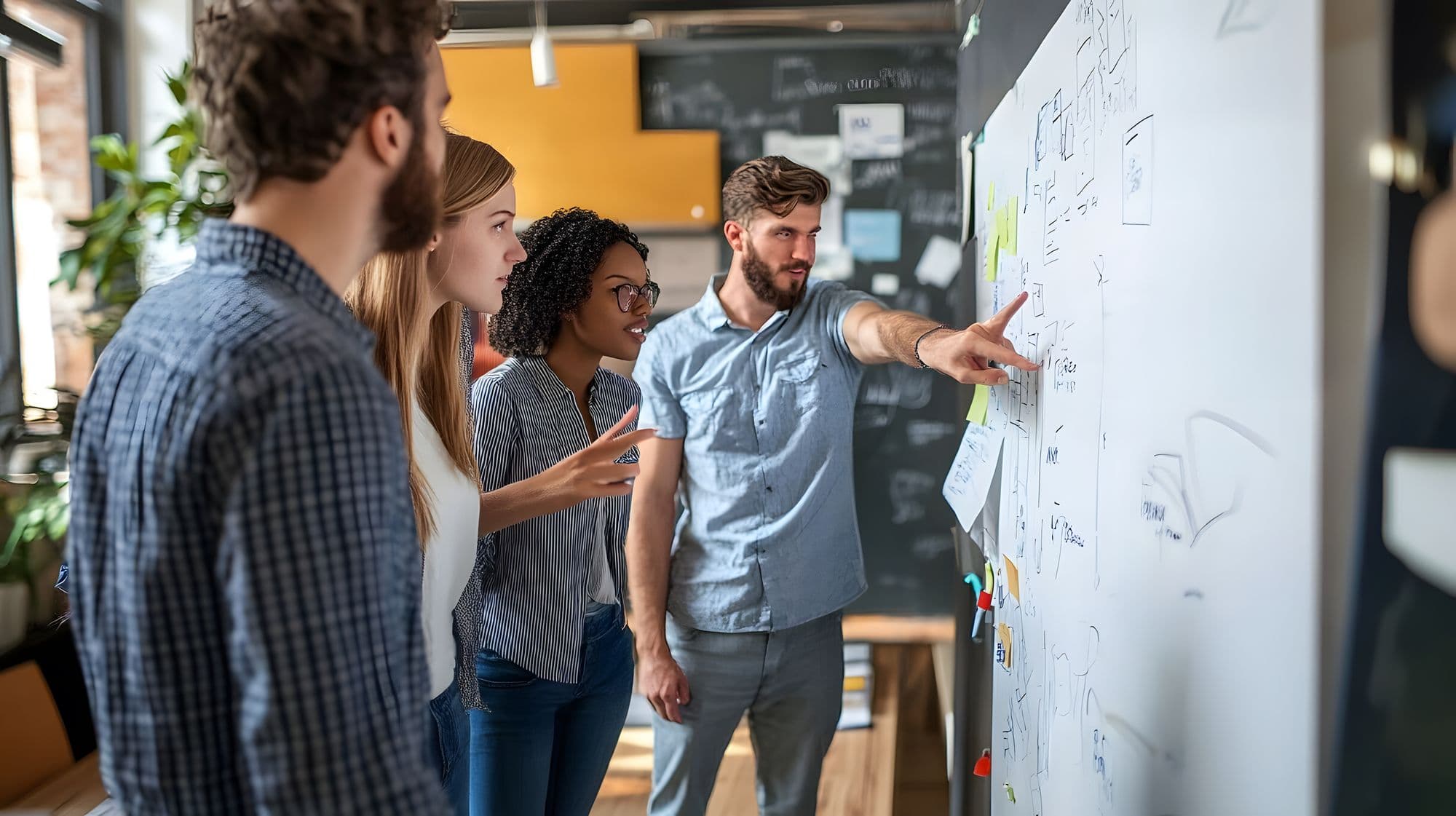 A team of four people brainstorming ideas on a whiteboard in an office